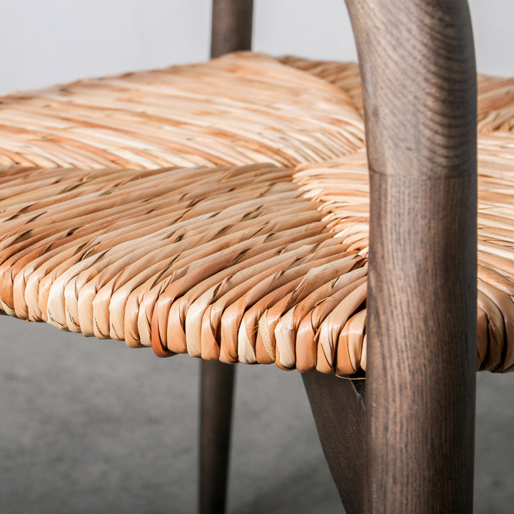 Close-up view of the Essence Dining Chair Leaf Rope/Smoke's woven leaf rope seat and dark wood frame.