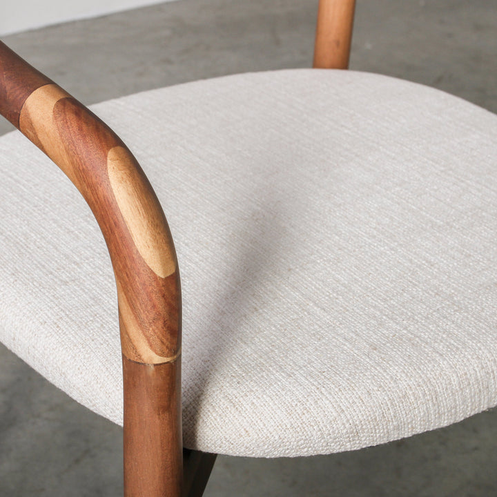 Essence Dining Chair Fabric/Walnut close-up showing the fabric seat and curved walnut wood armrest.