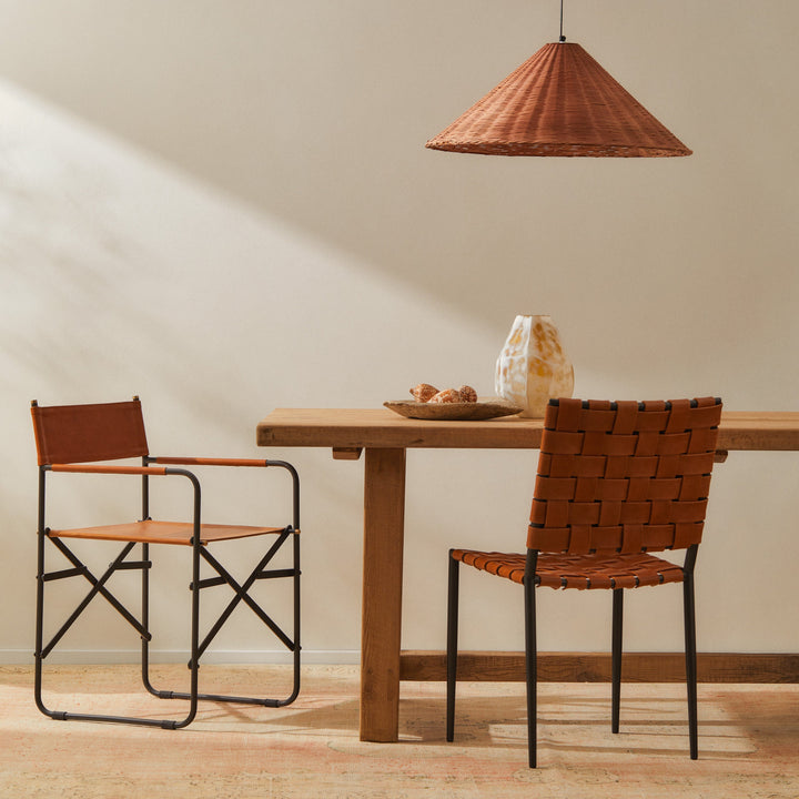Batali Dining Chair Tan beside a wooden table with woven leather strapping, showcasing modern dining furniture design.