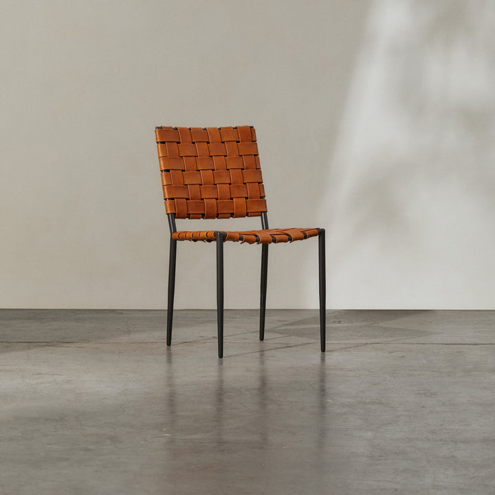 Batali Dining Chair Tan with woven leather strapping and metal framework in a contemporary setting.