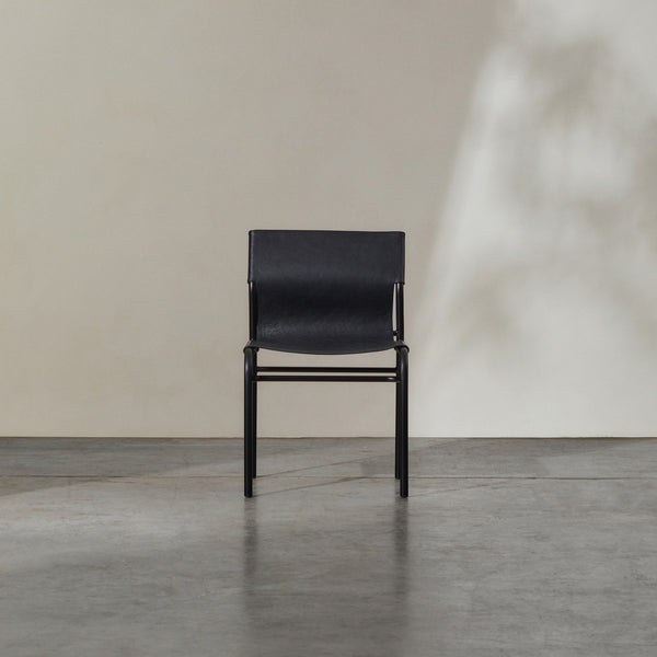 Fieri Dining Chair Black featuring a robust metal frame and premium leather upholstery in a minimalist setting.