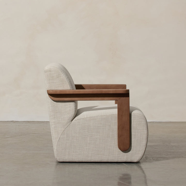 Corwin Occasional Chair Greige Our Corwin Occasional Armchair is mid-century inspired statement piece that blends sculptural elegance and grounded design. This unique upholstere chair features wooden arms that seamlessly extend into the base, eliminating