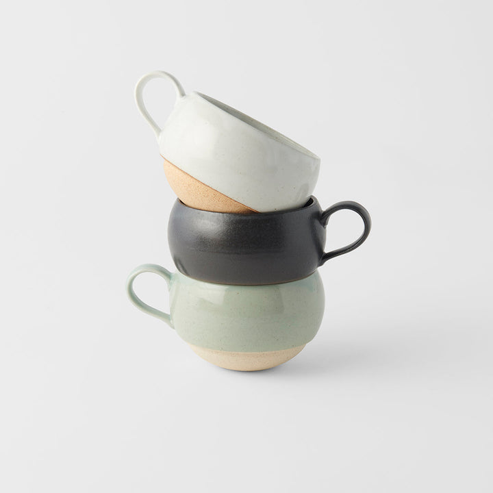 Stacked artisan mugs in black and green glaze, showcasing elegant design for tea and coffee.