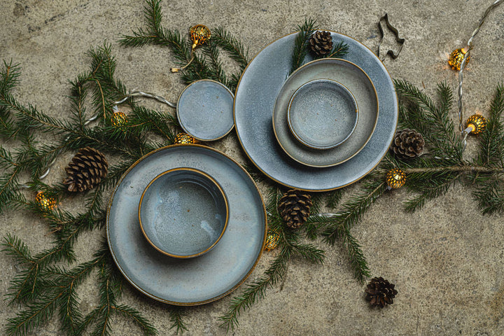 Oval 19cm steel grey bowl and plates with earthy brown outlines on natural greenery backdrop.