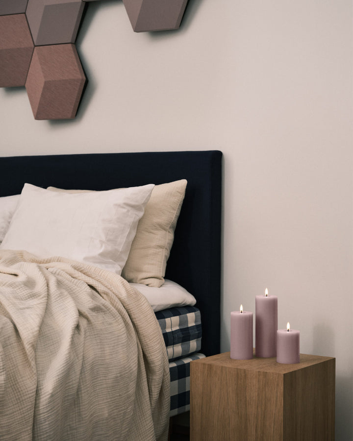 Cozy bedroom featuring Ester & Erik LED pillar candles with a lifelike glow on a wooden bedside table.