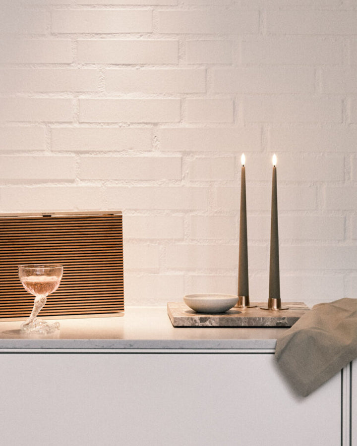 Ester & Erik LED taper candles in elegant setting with drink on marble surface, enhancing modern interior decor.
