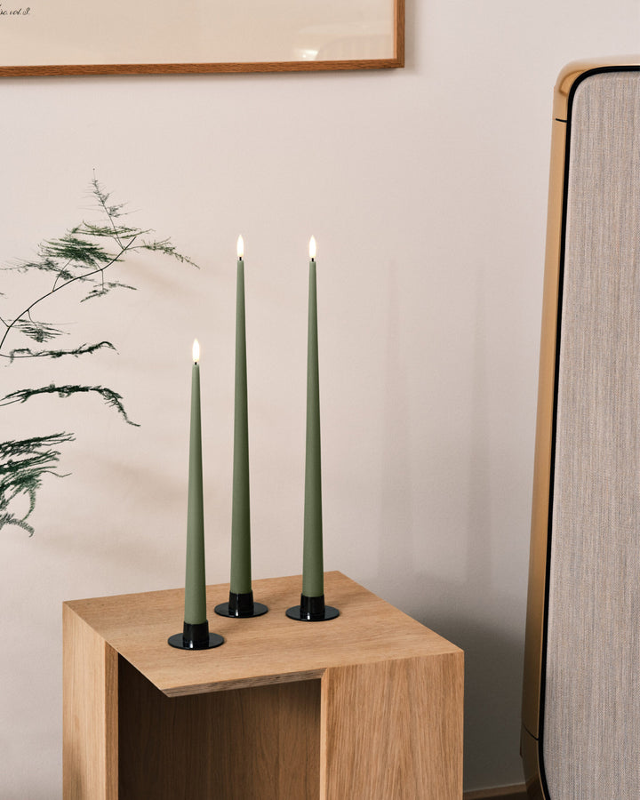 Ester & Erik LED taper candles in green on a wooden table, adding a touch of elegance to modern decor.