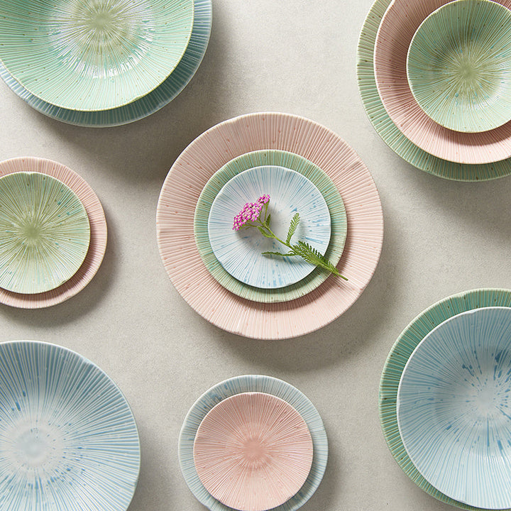 Colorful ceramic plates and bowls with radial texture, featuring ice blue, soft green, and pastel pink glazes.