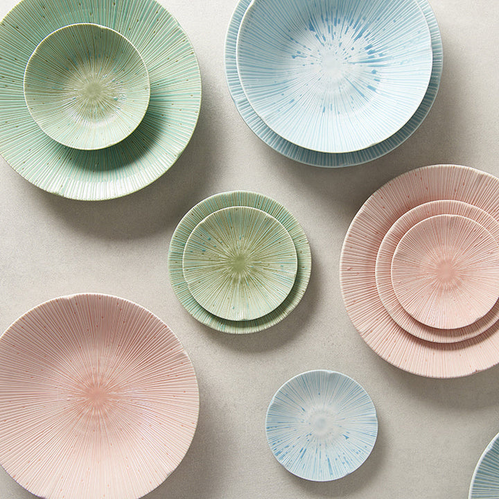 Assorted pastel ceramic bowls and plates with radial textures in shades of blue, green, and pink.