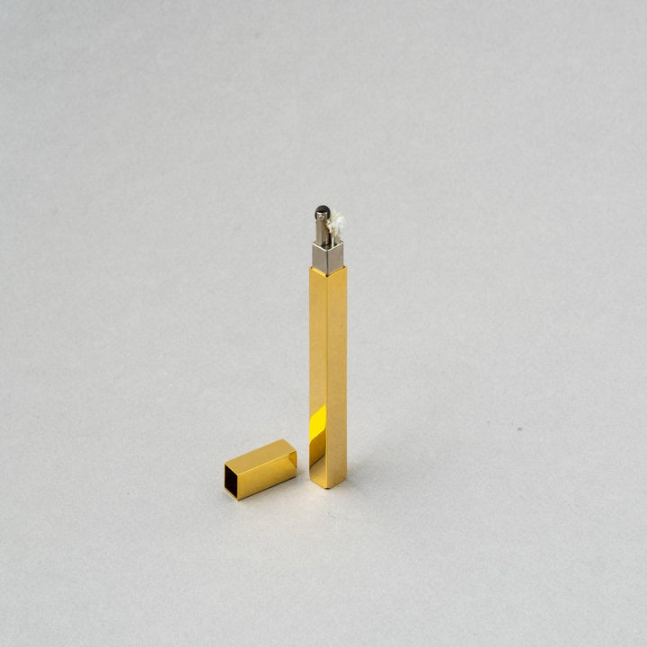 Gold metal refillable stick lighter by Tsubota Pearl, handcrafted in Tokyo, sleek and sophisticated design.