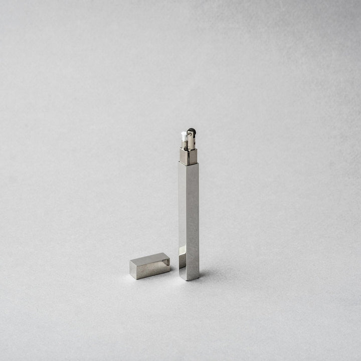 Tsubota Pearl Queue Silver Metal Petrol Lighter elegantly crafted from brass and steel, shown upright with cap beside it.