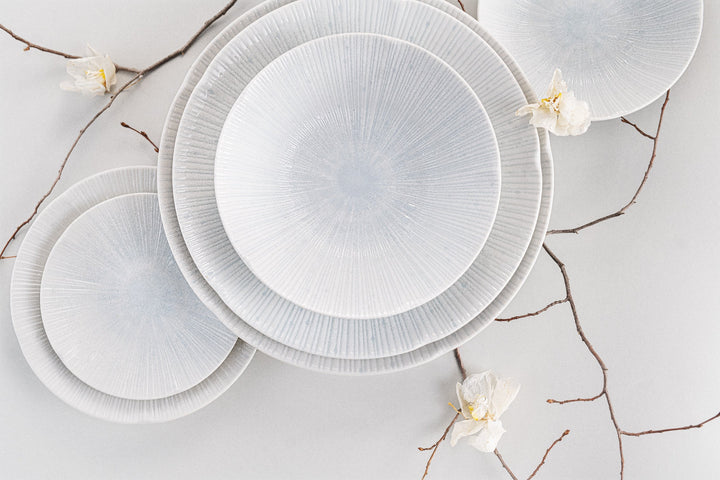 Elegant Ice White Bowls with radial texture arranged artistically, adorned with delicate flowers and branches.