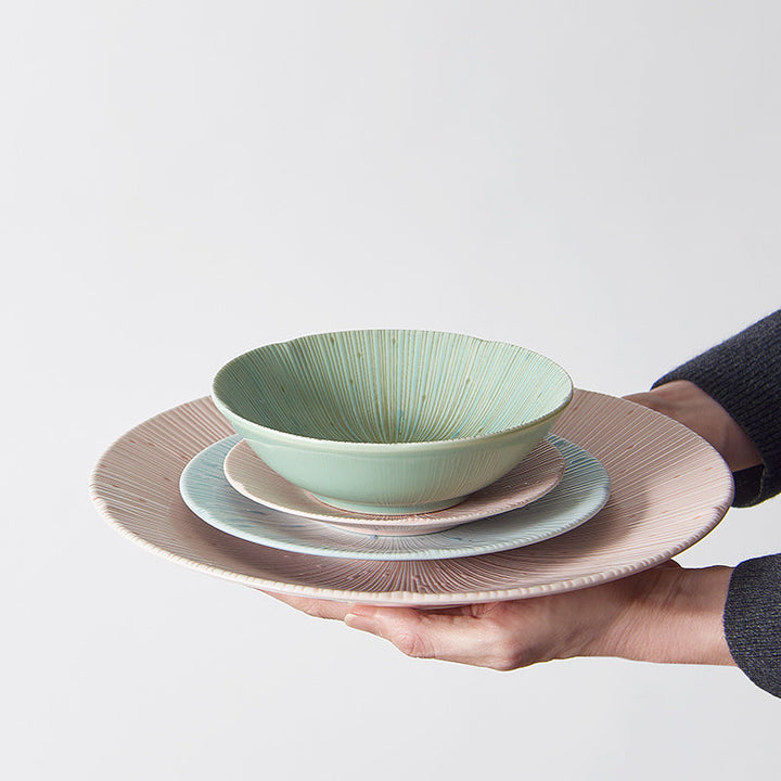 Elegant set of textured bowls and plates in soft colors, showcasing a modern tableware style for serving meals.