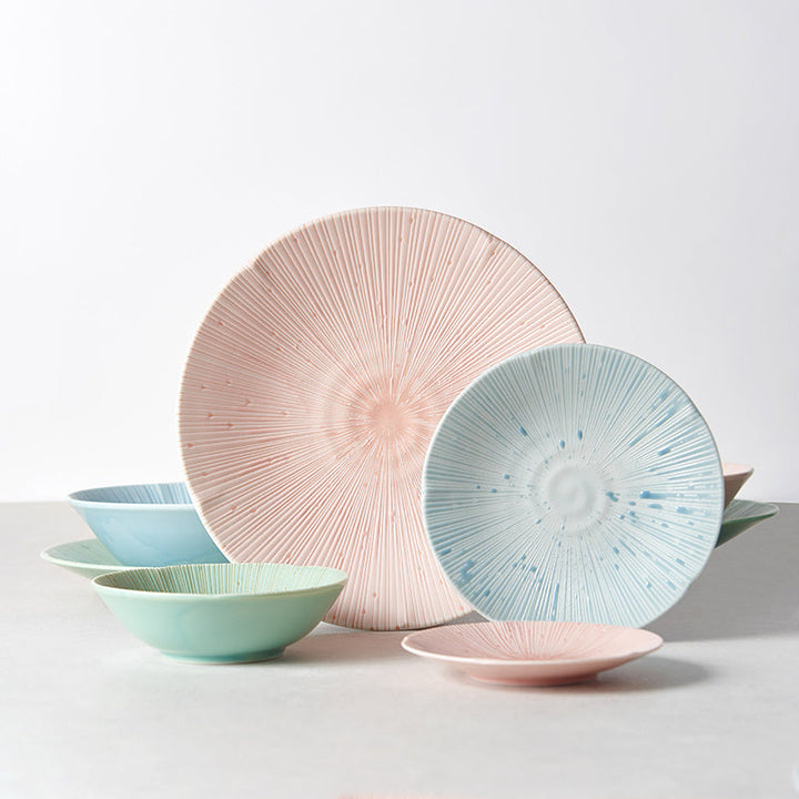 Colorful set of textured bowls and plates in pastel hues, featuring radial patterns for stylish table settings.