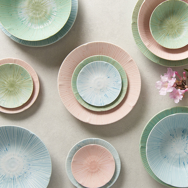 Colorful collection of textured plates and bowls in soft pastels, arranged beautifully on a neutral background.