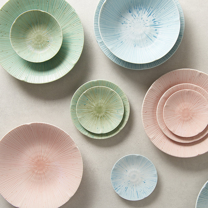 Assorted pastel-colored bowls and plates with radial texture in soft ice blue, green, and pink hues.