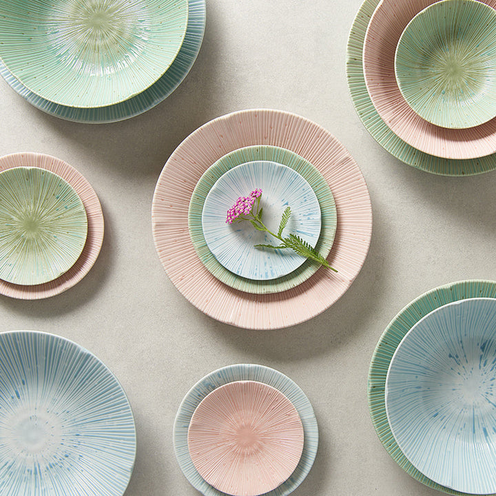Colorful ceramic plates and bowls with radial textures in ice blue, green, and pink showcasing a floral accent.