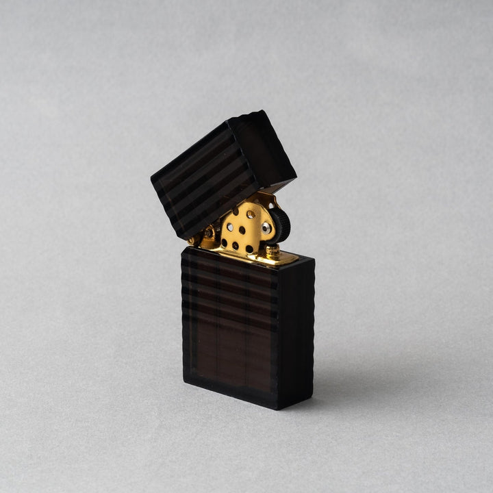 Tsubota Pearl Latitude Black petrol lighter with ridged casing and gold interior, handcrafted in Tokyo.