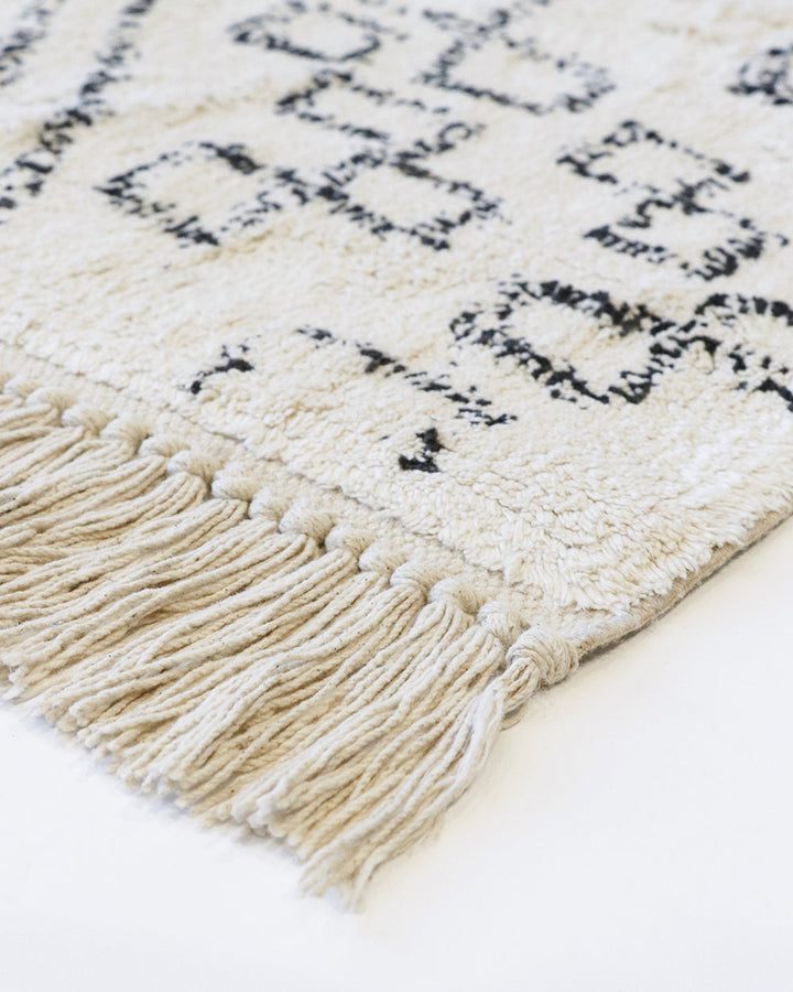 Awan Floor Rug Add a layer of comfort to your home with the soft 100% cotton tufting of the Awan. Featuring a shaggy pile and primitive patterning, the design is finished with a relaxed tassel edge. The casual aesthetic brings a well-travelled, welcoming