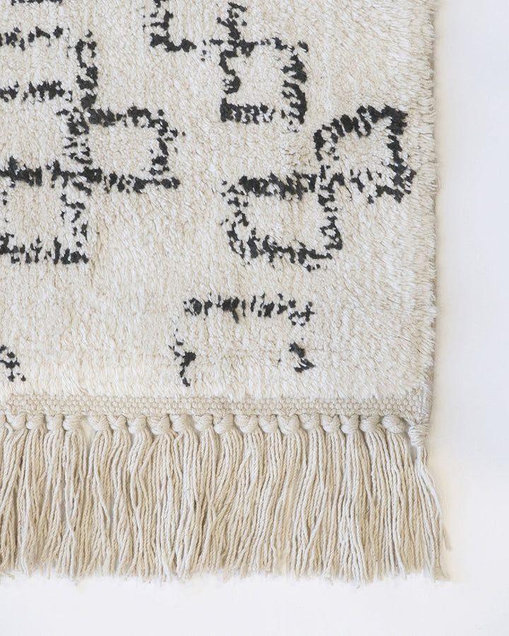 Awan Floor Rug Add a layer of comfort to your home with the soft 100% cotton tufting of the Awan. Featuring a shaggy pile and primitive patterning, the design is finished with a relaxed tassel edge. The casual aesthetic brings a well-travelled, welcoming