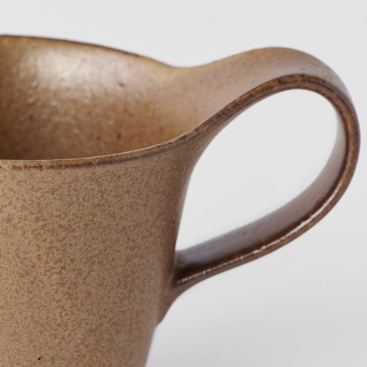 Close-up of a handmade 250ml chestnut brown glaze coffee mug featuring an elegant handle.