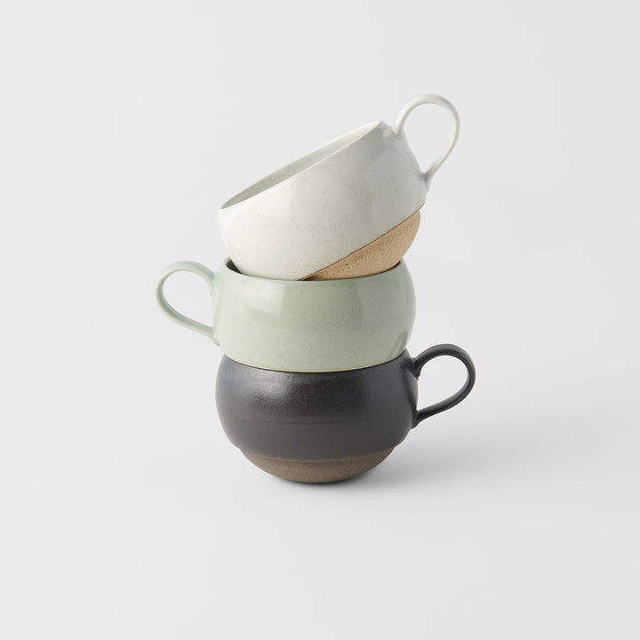 Stacked ceramic mugs in green, white, and black glaze; perfect for enjoying tea or coffee.
