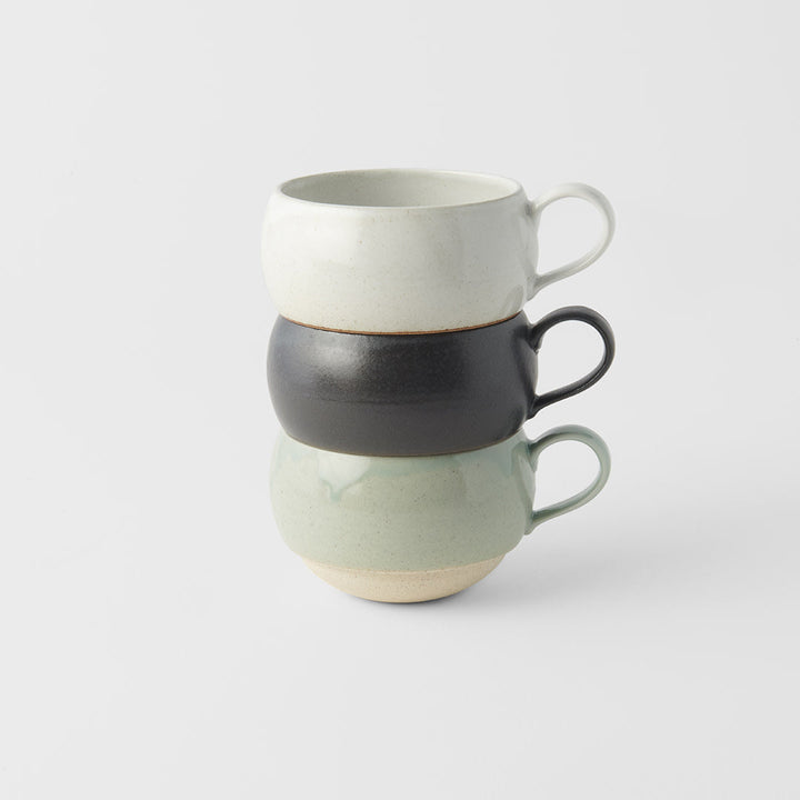 Stack of three artisan mugs in black glaze and calming pastel colors perfect for tea or coffee.