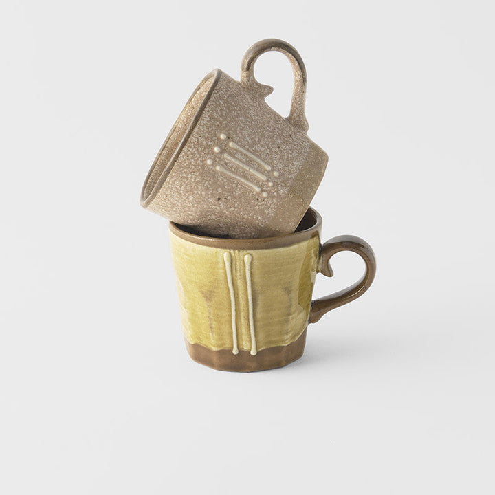 Stacked mug set in earth tones with glaze, showcasing textured finishes and intricate design details.