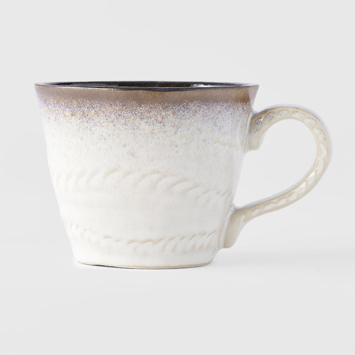 Handcrafted ceramic mug with white glaze and brown accents, showcasing artisan texture and unique design.