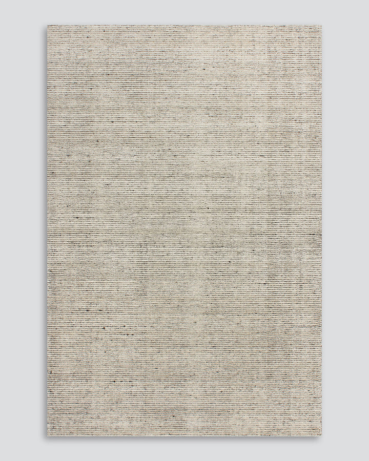 Emmett Floor Rug An understated floor rug that is both simple and luxurious. The Emmett is hand-knotted from 100% wool, creating a soft minimal pile. Featuring a fine linear pattern with a lighter base tone, this floor rug is perfect for crafting a refine