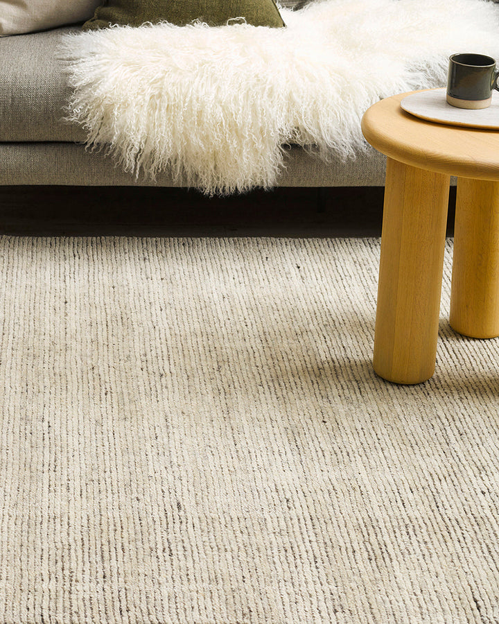 Emmett Floor Rug An understated floor rug that is both simple and luxurious. The Emmett is hand-knotted from 100% wool, creating a soft minimal pile. Featuring a fine linear pattern with a lighter base tone, this floor rug is perfect for crafting a refine