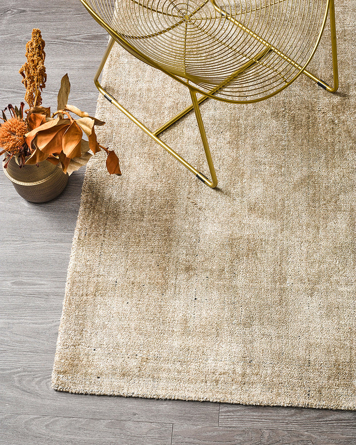 Gratus Floor Rug Indulge in the subtle sheen, rich fibre, and silky underfoot texture of Gratus. Handcrafted from a stunning blend of bamboo silk and wool, the muted gold colouring is complemented by a darker base undertone. Beautifully soft, the gentle l