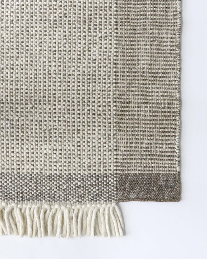 Lindis Floor Rug Add understated chic to your interior with the exceptional design of our Lindis floor rug. Handwoven by skilled artisans, tonal fibres are woven in a classic 1-1 structure, creating a refined and interesting border design. Fringing on bot