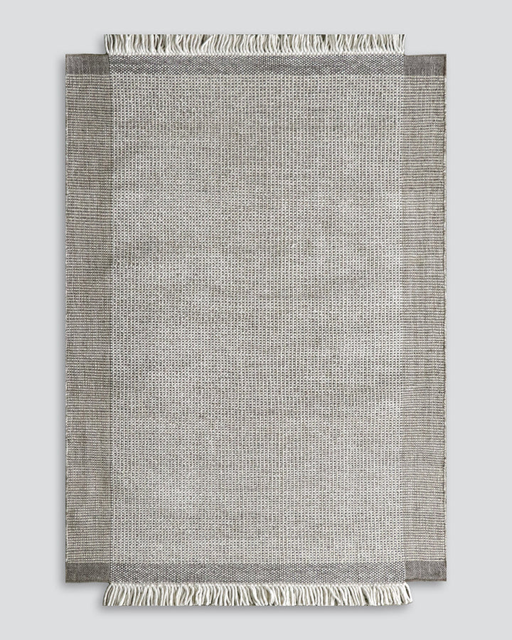 Lindis Floor Rug Add understated chic to your interior with the exceptional design of our Lindis floor rug. Handwoven by skilled artisans, tonal fibres are woven in a classic 1-1 structure, creating a refined and interesting border design. Fringing on bot