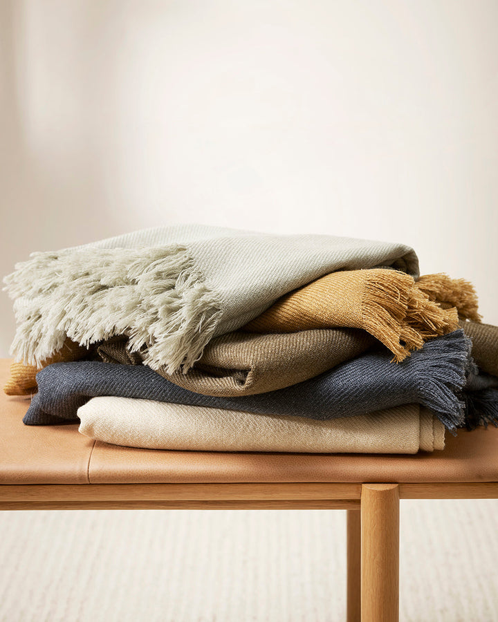 Altona Throw Add a pared-back accent to your space with the lightweight softness of Altona. Finely woven from a blend of wool and recycled polyester, the solid colour and delicate fringe edge makes this piece easy to style into most interior schemes. The