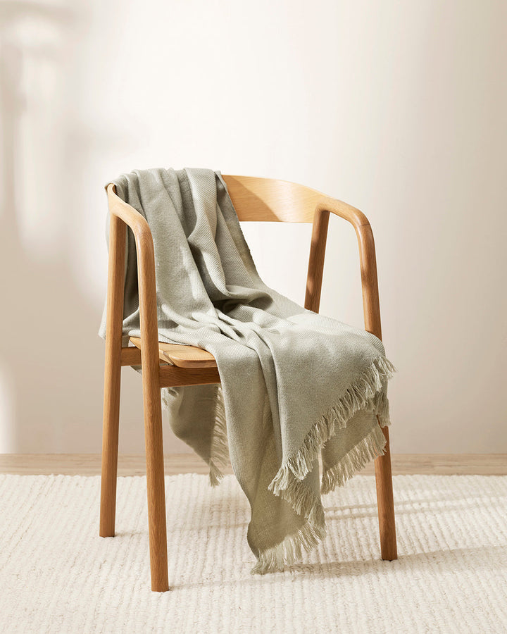 Altona Throw Add a pared-back accent to your space with the lightweight softness of Altona. Finely woven from a blend of wool and recycled polyester, the solid colour and delicate fringe edge makes this piece easy to style into most interior schemes. The